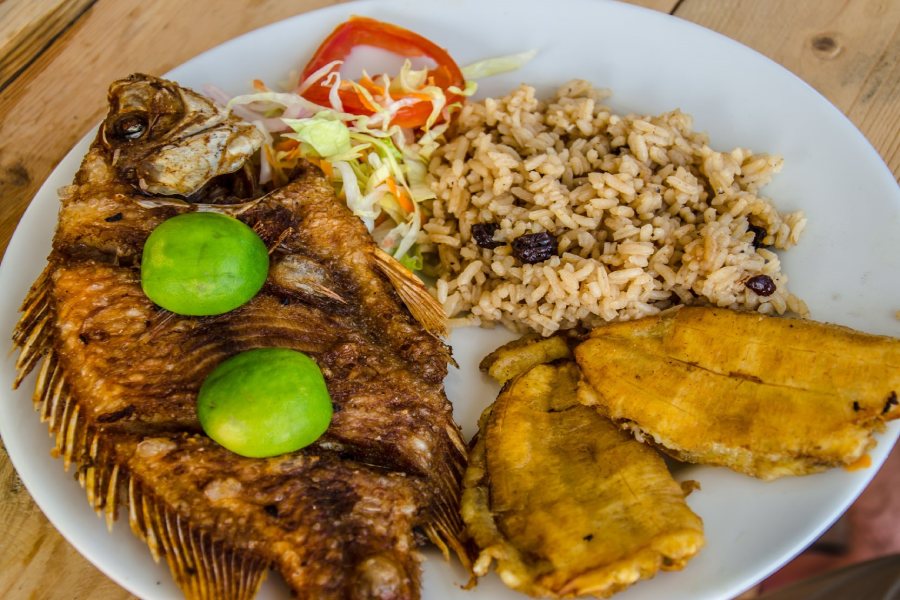 Pescado frito acompañado de arroz de coco y patacones.